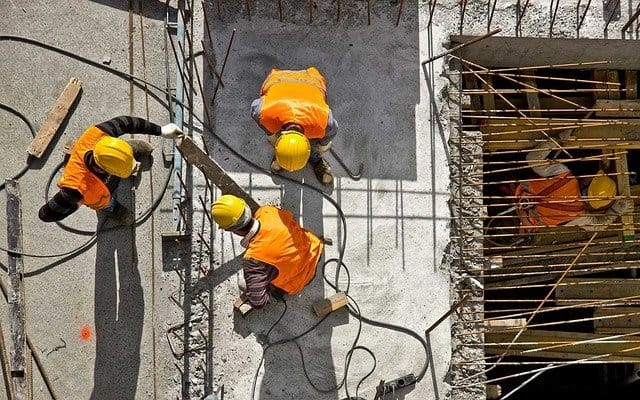 Prevención de riesgos laborales en construcción, trabajadores con casco y chaleco en obra.